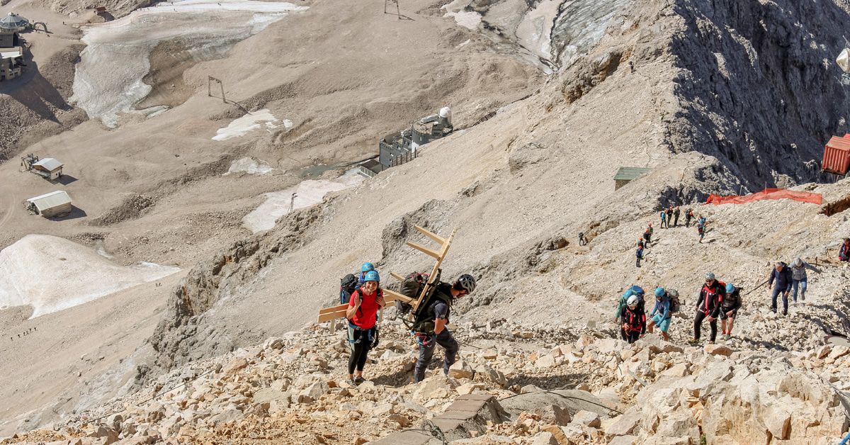 Hier wuchten sie eine Bank auf die Zugspitze. Aber warum?
