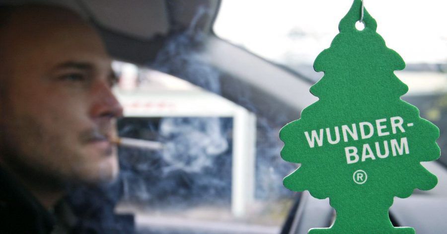 Ein Wunderbaum (Duftbaum) soll, während ein Mann raucht, in einem Auto die Luft verbessern. (Symbolbild)