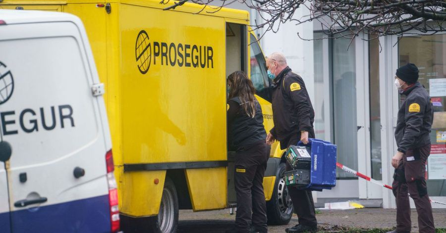 Nach einem Überfall auf den gelben Geldtransporter (hinten) sind mehrere Bewaffnete in Frankfurt/Main noch auf der Flucht.