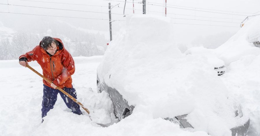 Ein Mann schaufelt sein eingeschneites Auto frei. Viele Walliser Täler sind wegen dem starken Schneefall von der Außenwelt abgeschnitten.