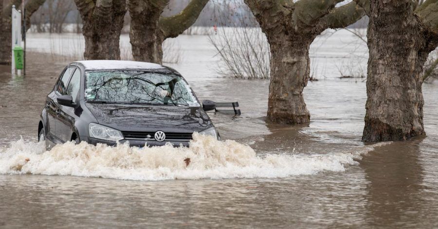 Ein Autofahrer steuert in Rüdesheim am Rhein seinen Wagen über eine vom Hochwasser überflutete Straße.