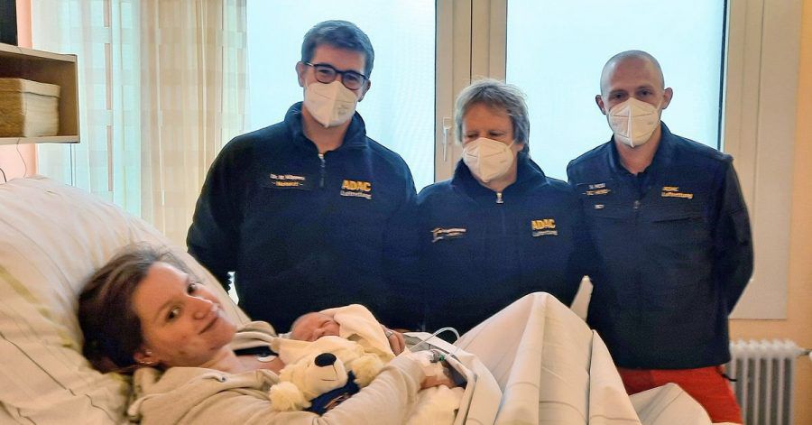 Mutter Sonja Lammers liegt mit Baby Martin Timotheus auf der Geburtsstation der Klinik Osnabrück. Dahinter stehen die "fliegenden Geburtshelfer" vom ADAC.
