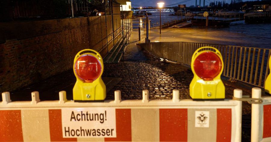 Ein Schild an einer Absperrung warnt vor Hochwasser, nachdem das Wasser des Rheins die Uferstraße in Rodenkirchen überflutet hat.