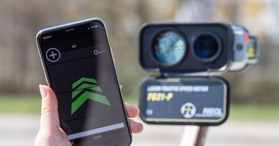 Links eine aktive Blitzer-Warnapp auf dem Smartphone, rechts daneben ein Radar-Messgerät.