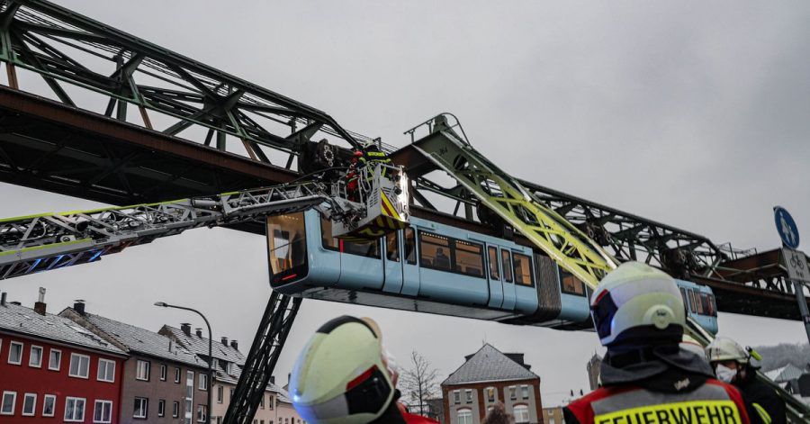 Einsatzkräfte der Feuerwehr befreien mit einer Drehleiter Fahrgäste aus einem Wagen der Schwebebahn, die wegen des eisigen Wetters stehen geblieben ist.