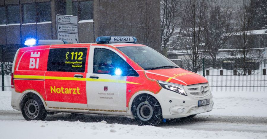 Ein Notarztwagen vom Rettungsdienst fährt mit Blaulicht auf einer zugeschneiten Straße in Bielefeld.