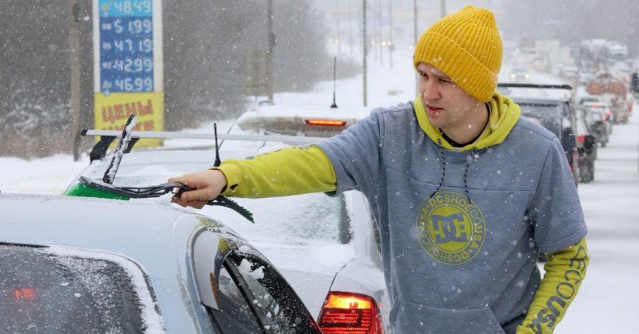 Kurz vor der Fahrt: Ein Mann wischt Schnee von seinem Auto.