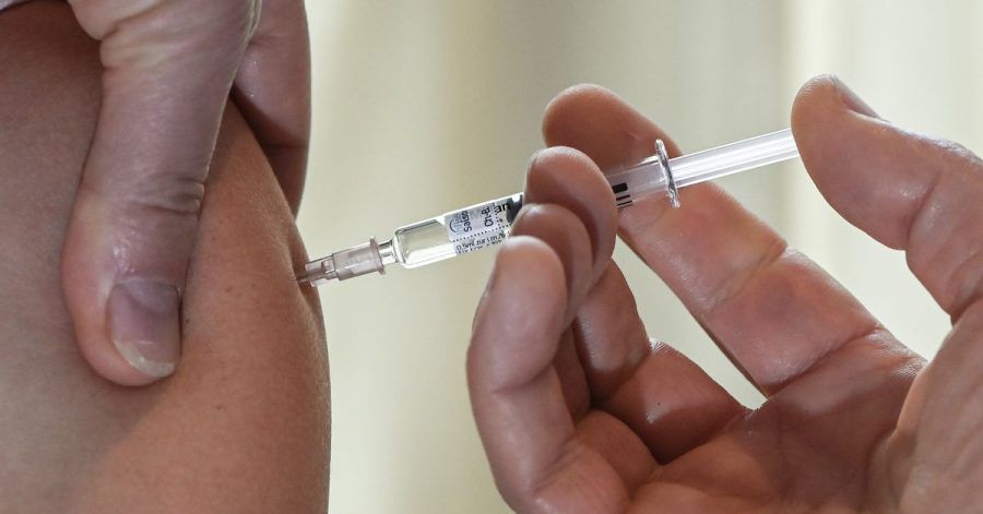 Ein Arzt impft eine Patientin gegen Grippe.
