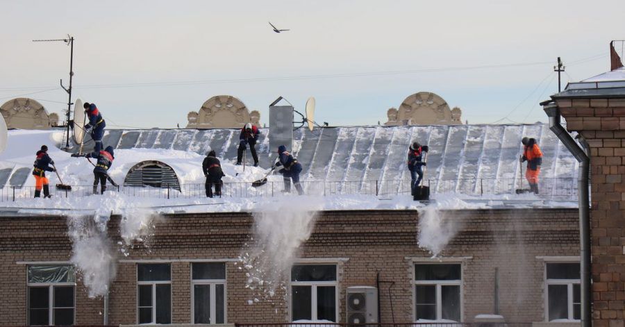Menschen schaufeln Schnee vom Dach eines Mehrfamilienhauses in Moskau.