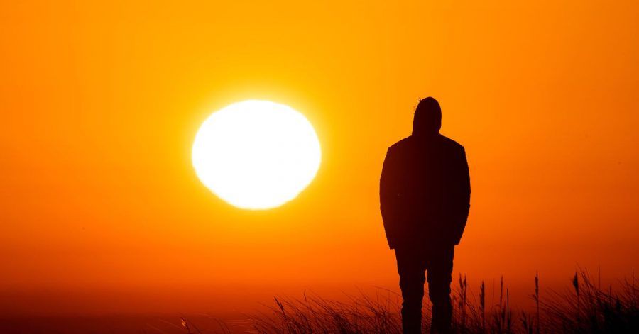 Ein Spaziergänger genießt am Strand von Schillig in Niedersachsen den Sonnenaufgang.