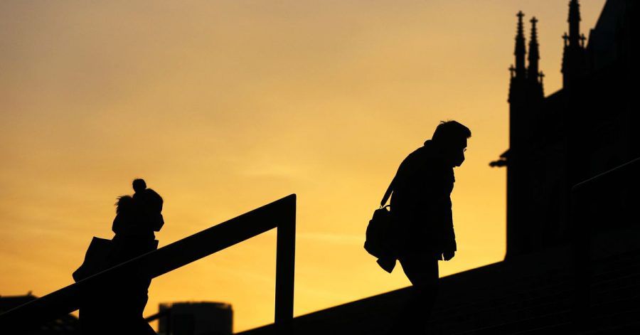 Menschen, die Schutzmasken tragen, gehen im Morgenlicht eine Treppe in Köln hinauf. Die sogenannte Sieben-Tage-Inzidenz in Nordrhein-Westfalen ist aktuell auf 61,7 gestiegen.