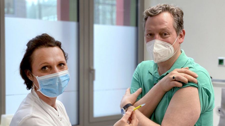 "Hirschhausen als Impfproband": Eckart von Hirschhausen lässt sich von Studienleiterin Professor Dr. Clara Lehmann (Uniklinik Köln) die Spritze setzen. (ili/spot)