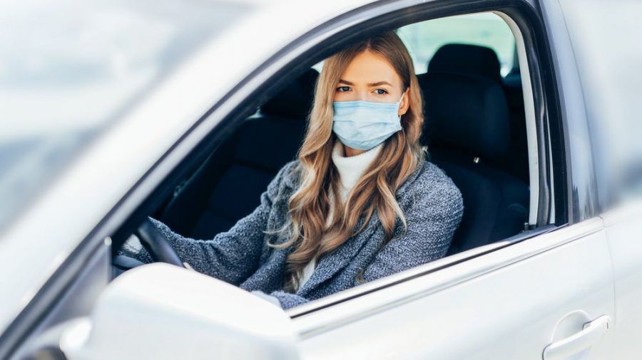 Eine junge Frau mit Schutzmaske im Auto (wue/spot)