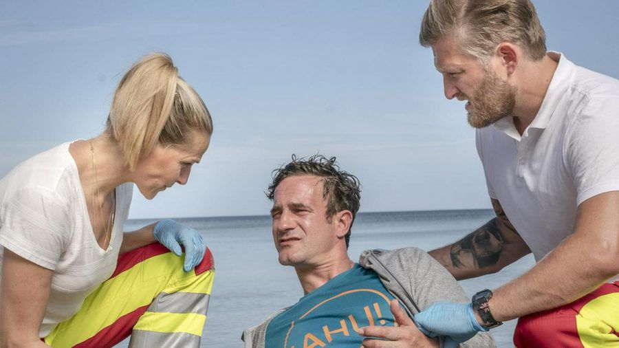 "Praxis mit Meerblick: Vatertag auf Rügen": Nora (Tanja Wedhorn) und Lars (Bo Hansen, r.) versorgen den Patienten Florian Becker (Sönke Möhring). (cg/spot)