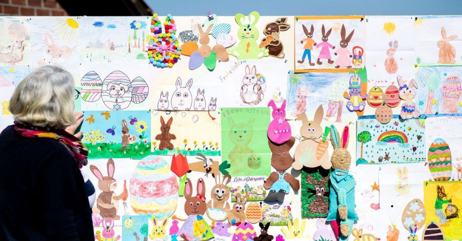 Doris Kröger, Mitarbeiterin im Osterpostamt, steht am Gemeindehaus vor einer Stellwand mit zahlreichen Briefen, die Kinder für den Osterhasen Hanni Hase geschrieben haben.
