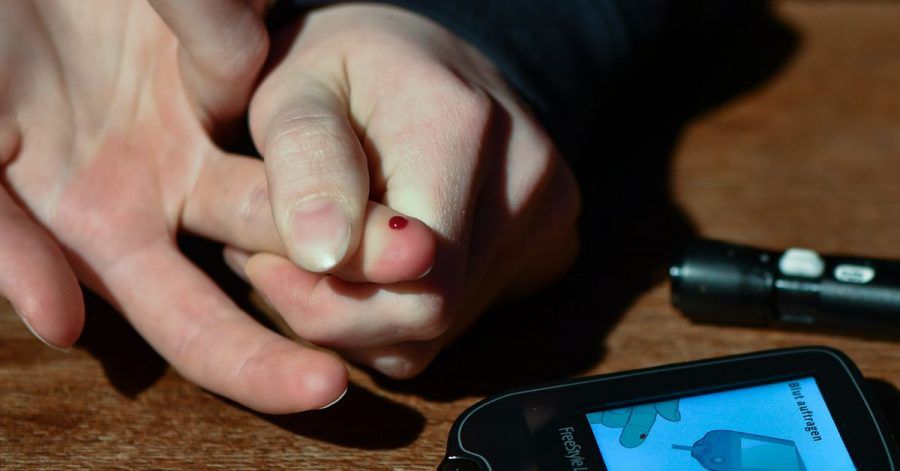 Ein Mädchen, das an Diabetes Typ 1 erkrankt ist, misst mit einem Blutzuckermeßgerät ihren aktuellen Zuckergehalt im Blut.
