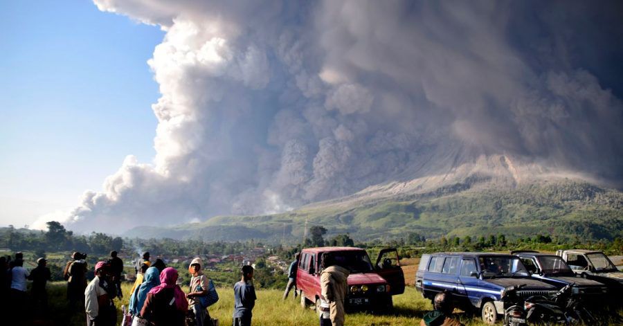 Menschen beobachten eine Eruption des Vulkans Sinabung.