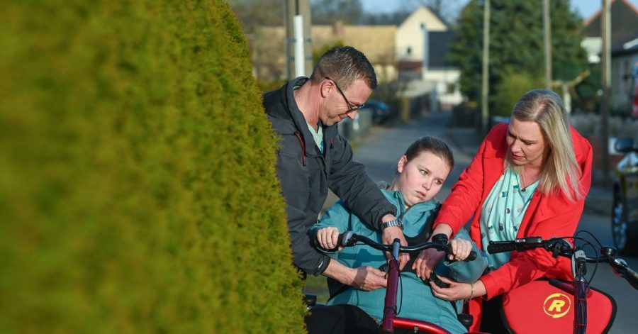 Vater David und Mutter Madeleine schnallen Vanessa auf dem Therapietandem an - dann drehen sie eine Runde durchs Dorf.