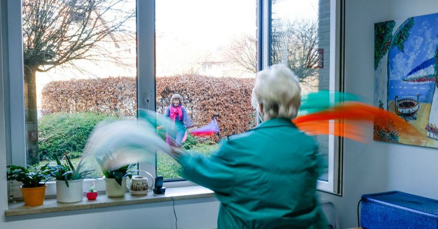 Übungsleiterin Babette Rackwitz-Hilke (l) von der TSV Reinbek macht Gymnastikübungen mit Tüchern vor, die Marianne Pinkus am Fenster wiederholt.