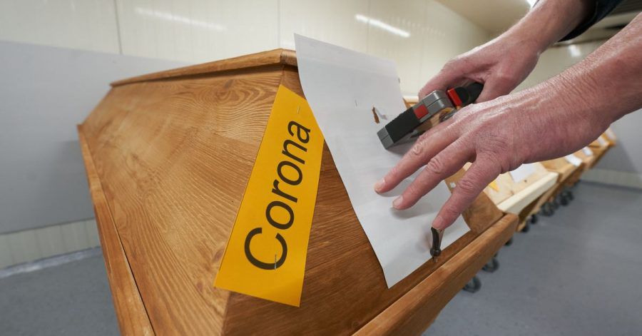Ein Mitarbeiter des Krematoriums in Dachsenhausen (Rheinland-Pfalz) bringt an einem Sarg die Markierung «Corona» an.