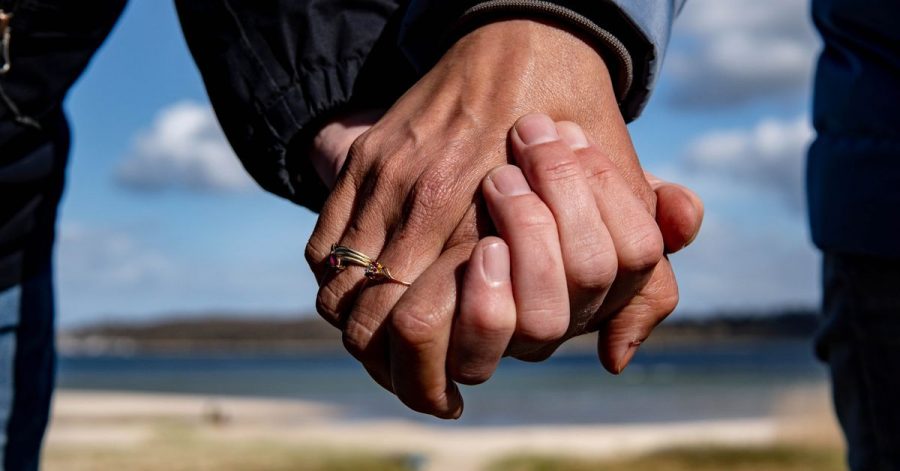 Eine Frau und ein Mann halten sich bei einem Strandspaziergang an den Händen.