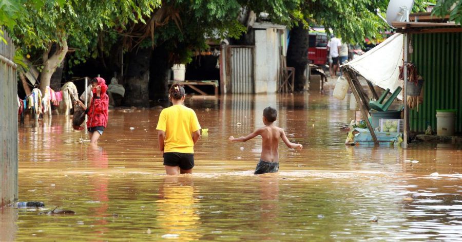 Menschen waten in Dili durch das Hochwasser.