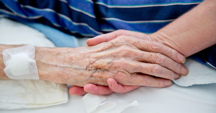 Eine Krankenpflegerin der Onkologie im Klinikum in Nürnberg hält die Hand eines Patienten.