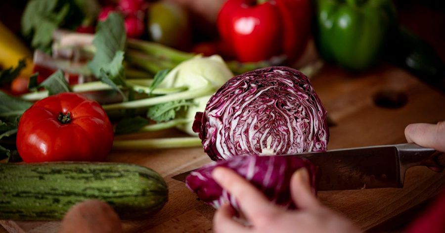 Eine Frau schneidet auf einem Schneidbrett mit einem Küchenmesser einen Radicchio.