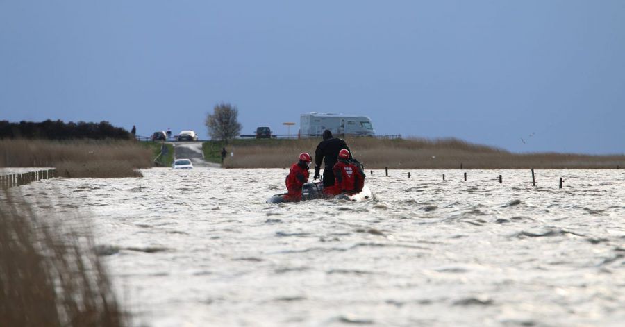 Rettungskräfte im Meer vor Ostfriesland, die von der Flut überraschten Ausflüglern helfen.