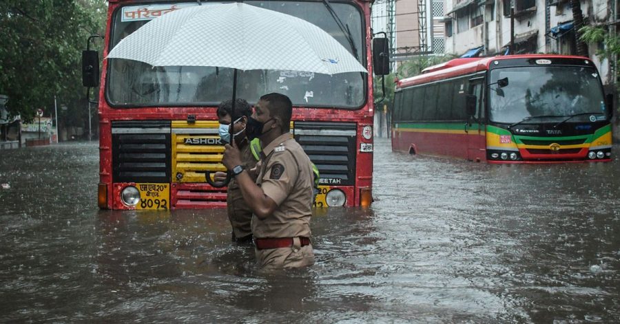 Ein Polizist hilft in Mumbai einem Fahrer eines öffentlichen Verkehrsmittels, eine überschwemmte Straße zu überqueren.