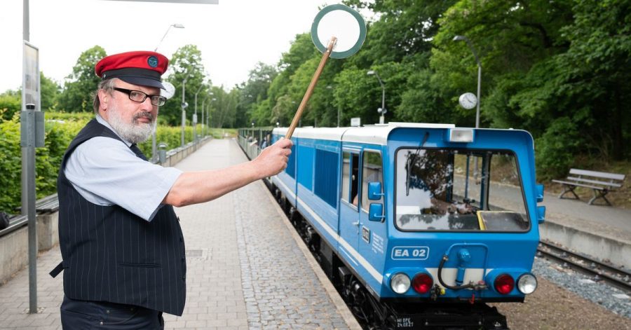 Uwe Schneider, Mitarbeiter der Parkeisenbahn Dresden, hebt am Hauptbahnhof die grüne Kelle zur Abfahrt.