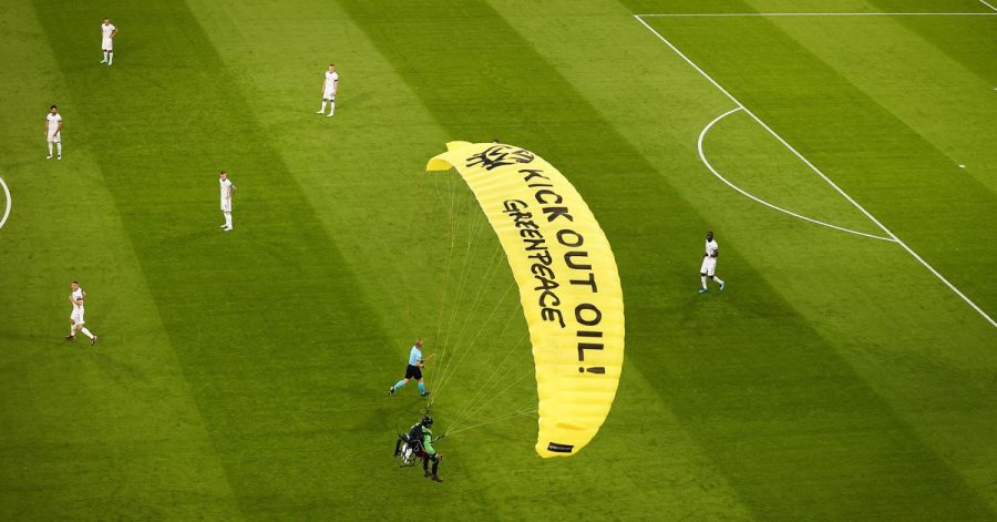 Ein Greenpeace-Aktivist landet mit einem Motorschirm-Flieger bei einer Protestaktion auf dem Spielfeld.