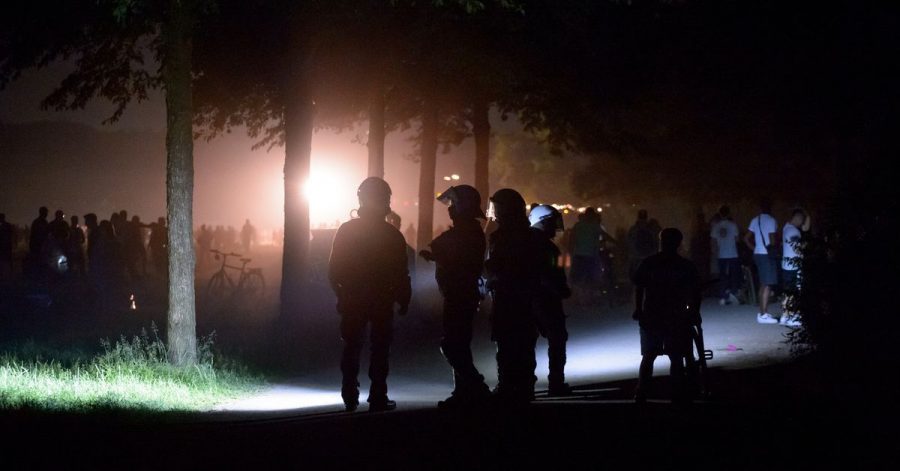 Behelmte Polizisten stehen am Rande der Stadtpark-Wiese und werden von einem Lichtmast angestrahlt. Die Polizei hat eine Party mit rund 3000 Menschen im Hamburger Stadtpark aufgelöst.