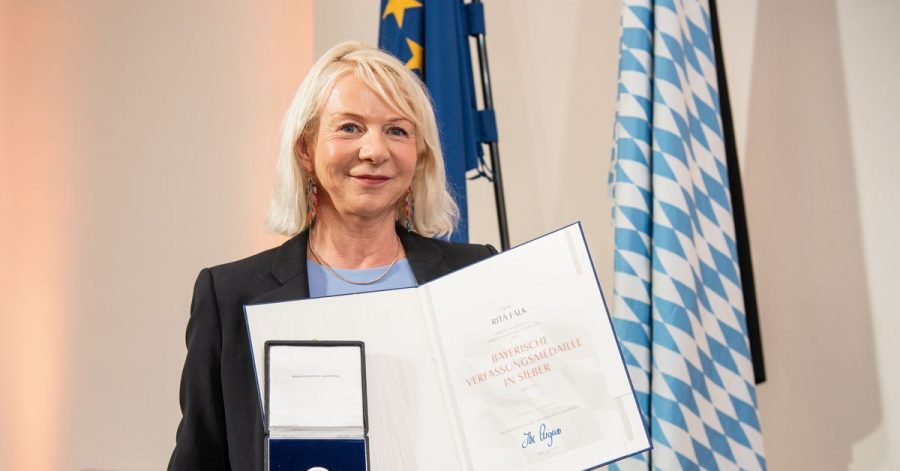 Rita Falk, Autorin, hält bei der Verleihung der Bayerischen Verfassungsmedaille im Landtag ihre Urkunde und Medaille in den Händen.