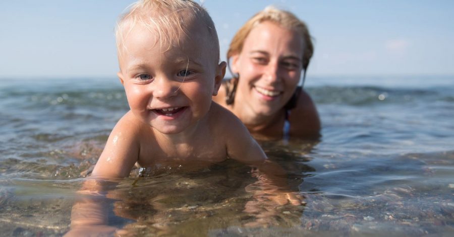 Ein kleiner Junge planscht vergnügt am Ufer. Seine Mama bleibt konsequent in Griffweite - so kann sie zupacken, falls etwas passiert.