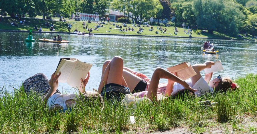 Drei Frauen liegen auf der Wiese am Landwehrkanal in Berlin und lesen Bücher.