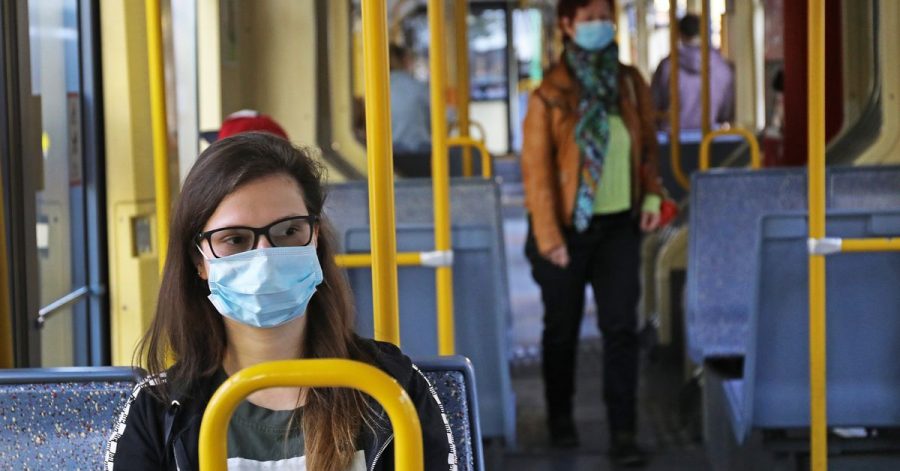 Cathrine sitzt mit einer Schutzmaske in einer Straßenbahn.