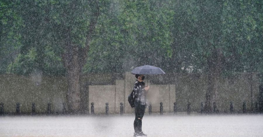Eine Frau in London schützt sich mit einem Schirm vor dem starken Regen.