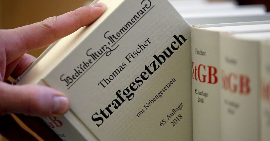 Illustration - Ein Jurist nimmt das Strafgesetzbuch aus dem Regal. In Bayern muss sich ein junger Polizist unter anderem wegen des Besitzes kinderpornografischer Schriften vor einem Gericht verantworten.