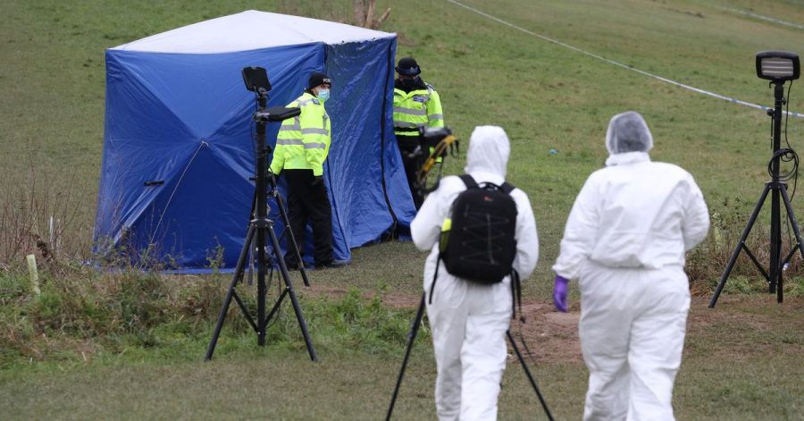 Zwei Gerichtsmediziner gehen zu einem Zelt am Tatort auf dem Bugs Bottom Feld. Fünf Jugendliche sollen hier im Januar einen 13-jährigen Jungen erstochen haben.
