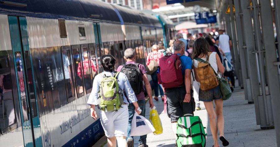 Voller Bahnsteig: Reisende gehen auf der Nordseeinsel im Bahnhof Westerland an einem Zug entlang.