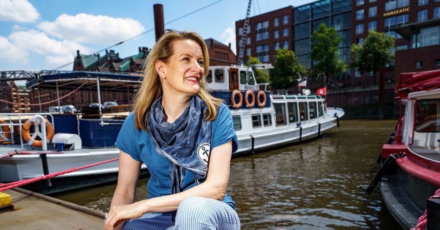 Tourguide Maike Brunk sitzt vor einer Tour durch den Hamburger Hafen vor einer Barkasse.