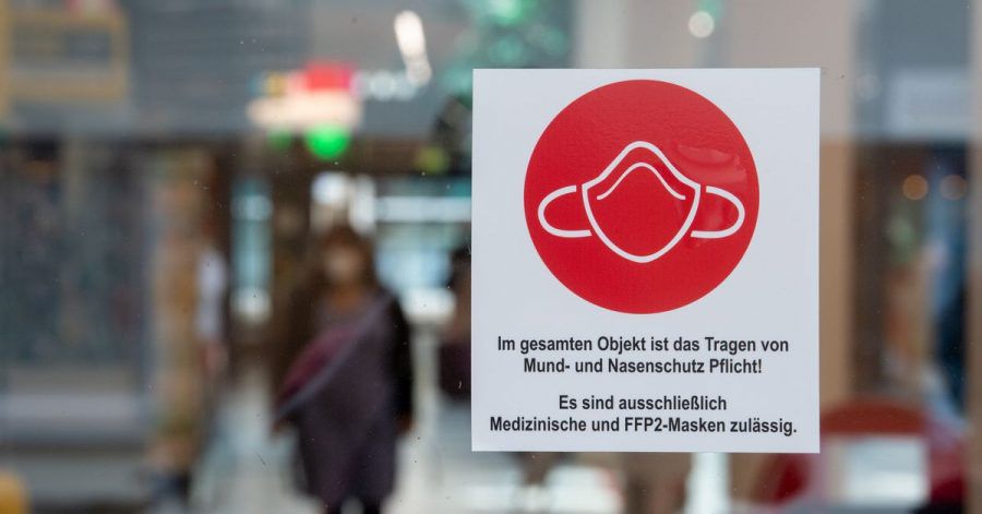 Ein Schild am Eingang zu einer Einkaufspassage weist auf das Tragen von Mund- und Nasenschutz hin.