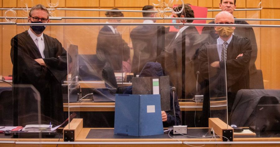 Der damals 27-Jährige Hauptangeklagte (vorne), seine Mutter (ganz hinten links) und ein dritter Angeklagter (roter Hefter) sitzen in einem Gerichtssaal des Landgerichts.