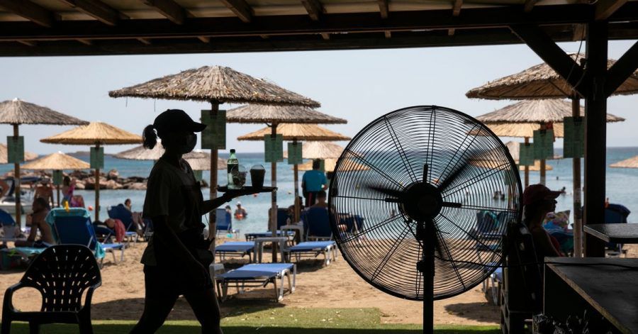 Eine Kellnerin serviert Erfrischungen in einer Strandbar im Dorf Lagonissi. Eine seit Anfang der Woche andauernde Hitzewelle in Griechenland erreicht ihren Höhepunkt.