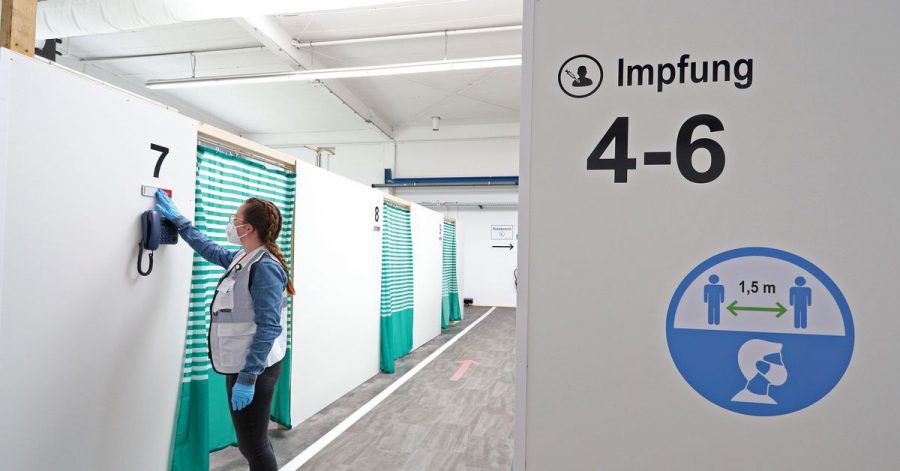 Eine Mitarbeiterin des Impfzentrums Attendorn richtet ein Schild vor einer Impfkabine im Impfzentrum.