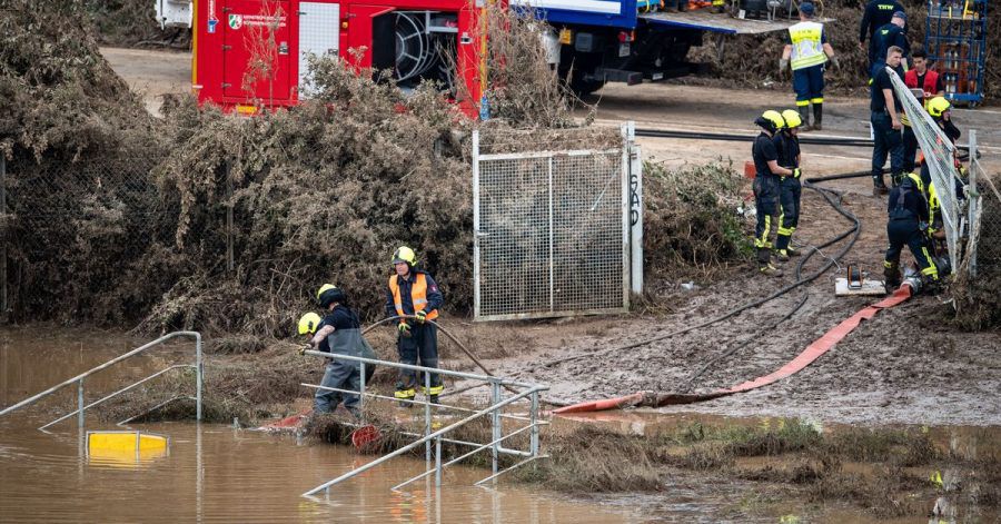 Helfer von Feuerwehr und Technischem Hilfswerk (THW) pumpen Wasser aus einem Regenrückhaltebecken ab, in dem sich noch Fahrzeuge befinden sollen.