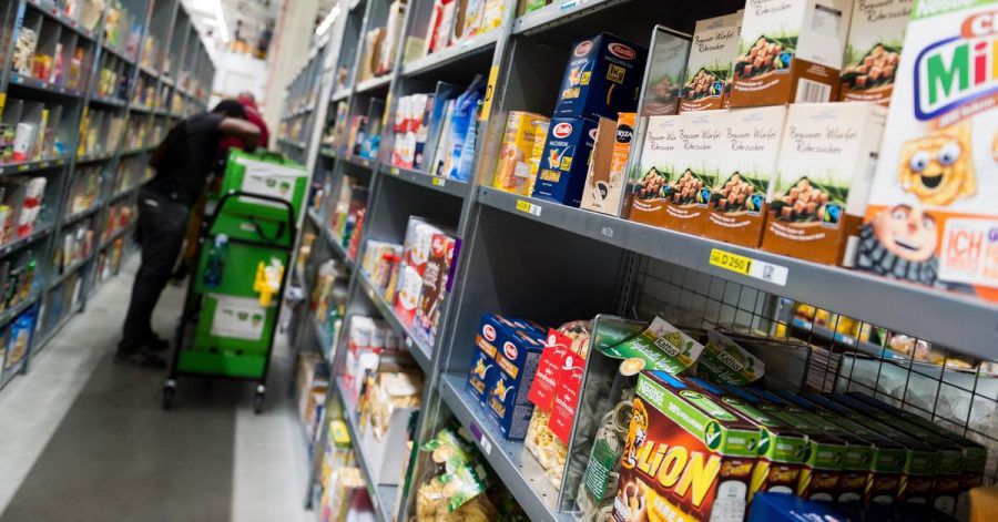 Ein Mitarbeiter eines Lebensmittellieferdienstes packt bestellte Waren ein. Der Online-Handel mit Lebensmitteln boomt.