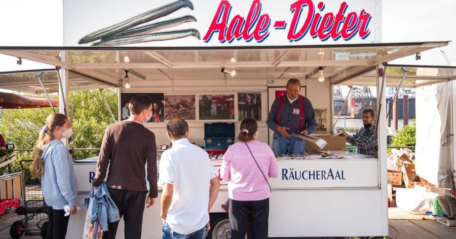 Besucher auf dem Hamburger Fischmarkt am Stand von Aale-Dieter.