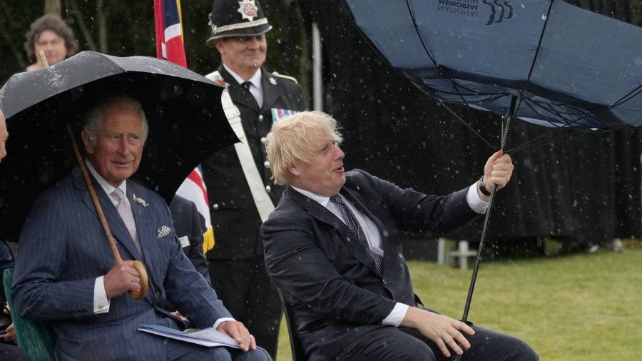 Prinz Charles (li.) kann sich ein Lächeln über Boris Johnsons Schirm-Problem nicht verkneifen. (hub/spot)